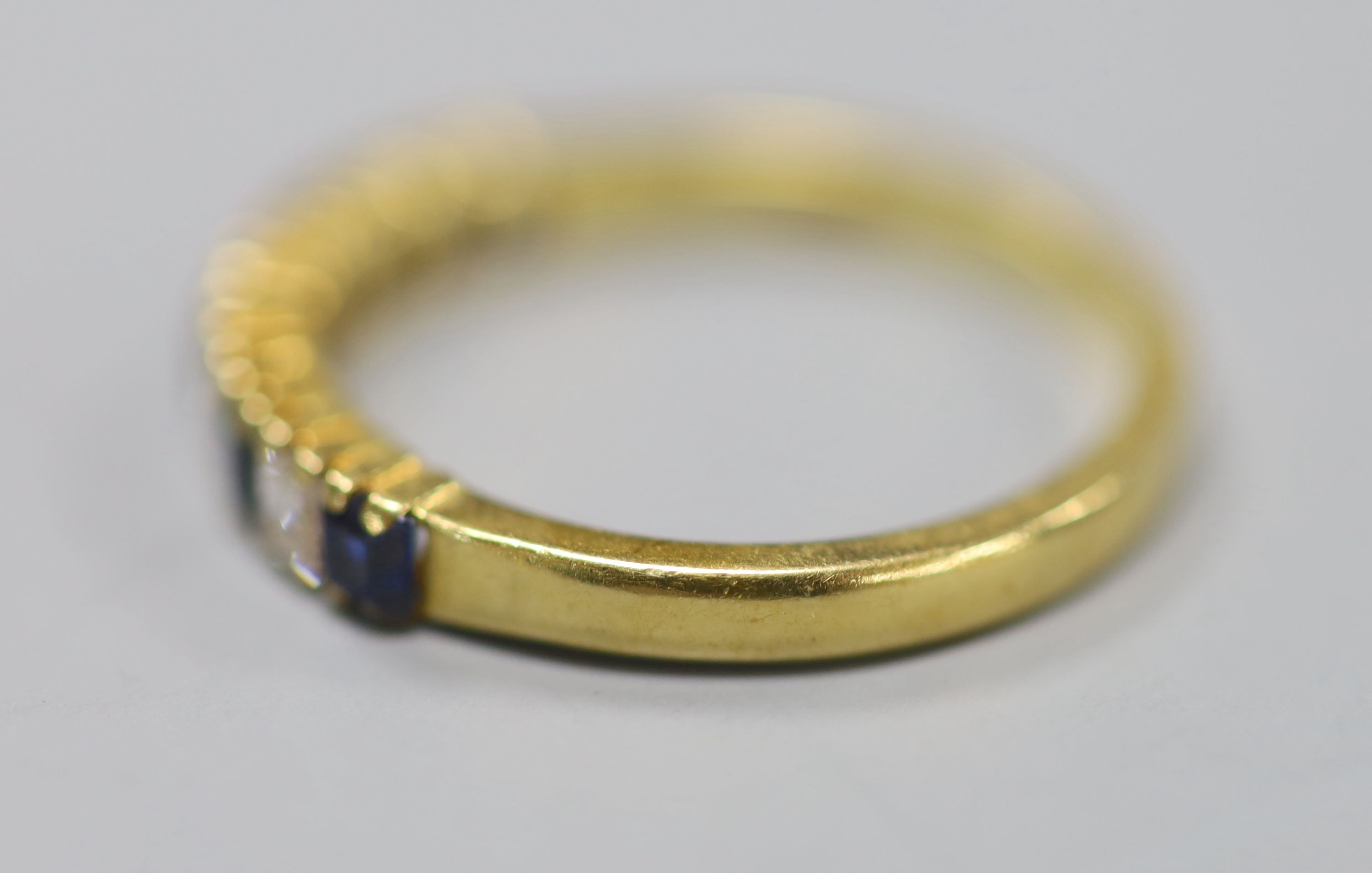 A modern 18ct gold, five stone sapphire and four stone diamond set half hoop ring, size M/N, gross 3.1 grams.